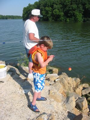 A boy and a man fishing on a bank
